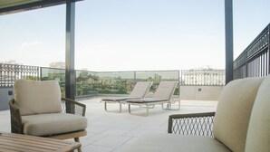 A balcony with two lounge chairs and a wooden table, overlooking a cityscape. - H41 Luxury Suites (Belgrade)