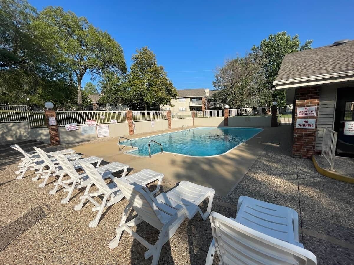 A swimming pool with lounge chairs and a no smoking sign.