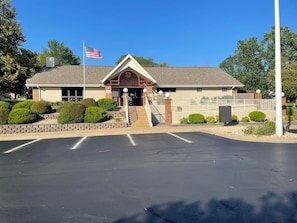 A building with a flag, a parking lot, and a clear sky. - Foothills Retreat (Branson)
