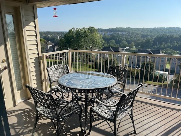 A covered outdoor area with a round glass table and four chairs.