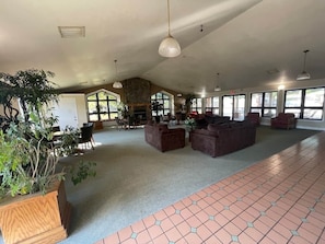 A spacious indoor area with multiple seating arrangements, a fireplace, and large windows allowing natural light.