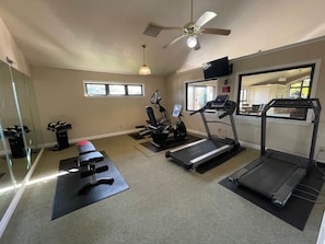 A home gym with exercise equipment including a treadmill, stationary bike, and weights.