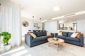 A modern living room with two grey sofas, a round coffee table, and a large potted plant.