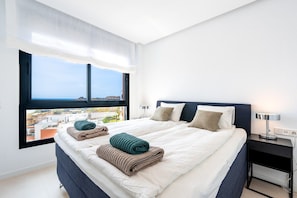 Une chambre d’hôtel avec un grand lit, une table de chevet, une lampe et une vue sur la ville par la fenêtre.