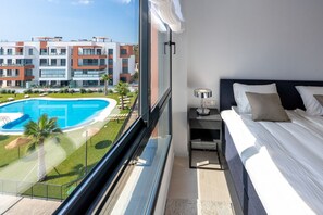 A modern hotel room with a large window overlooking a swimming pool and a well-maintained lawn. - Penthouse Middle Views | Luxury private terrace pool, sea view (Fuengirola)