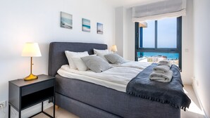 A modern bedroom with a large bed, bedside lamps, a view of the sea, and a window with a view of buildings. - Penthouse Middle Views | Luxury private terrace pool, sea view (Fuengirola)