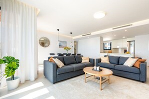 Ein modernes Wohnzimmer mit zwei Sofas, einem Couchtisch und einem Essbereich mit Stühlen.