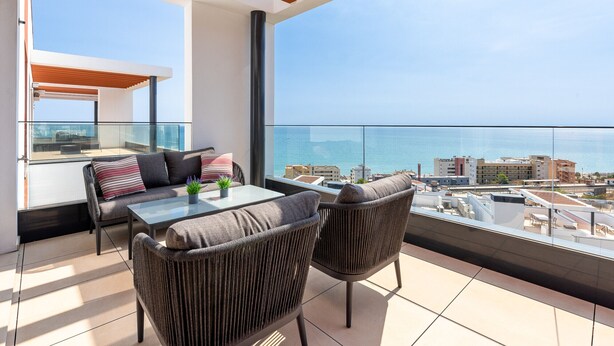 A balcony with a glass table, two wicker chairs, and a sofa with cushions. - Penthouse Middle Views | Luxury private terrace pool, sea view (Fuengirola)
