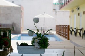 A poolside area with a white planter holding flowers and a small fountain. - Villas Dulce Sueños Residencial (Rincón de Guayabitos)