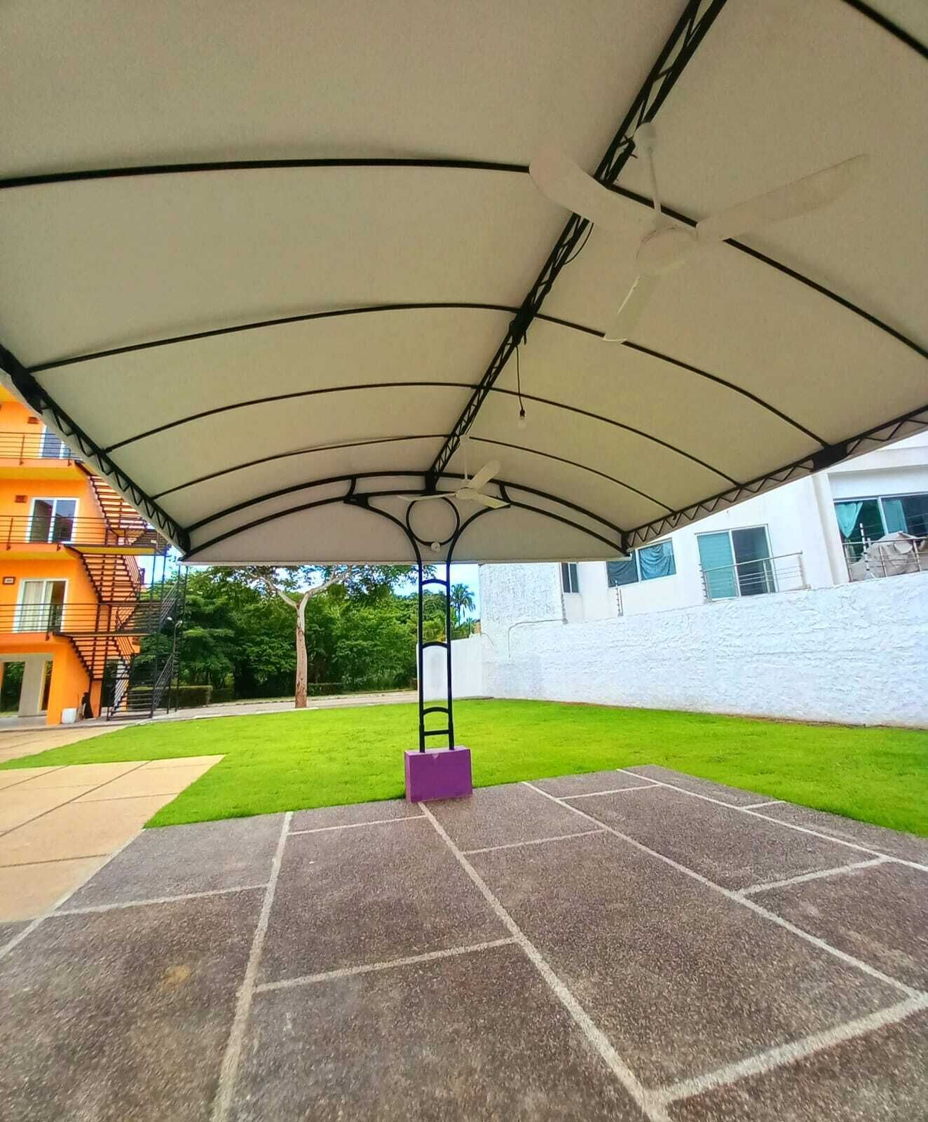 An outdoor covered patio area with a central pole and a white canopy.