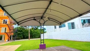 An outdoor covered patio area with a central pole and a white canopy.