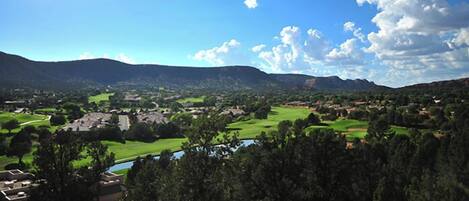 Una vista panorámica de un valle con un río, campos verdes y una cadena montañosa al fondo.
