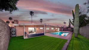 Et moderne hus med swimmingpool, terrasse og en stor kaktus.