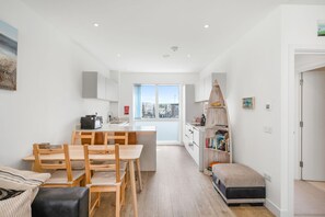 A modern apartment with a kitchen, dining area, and a small bedroom.