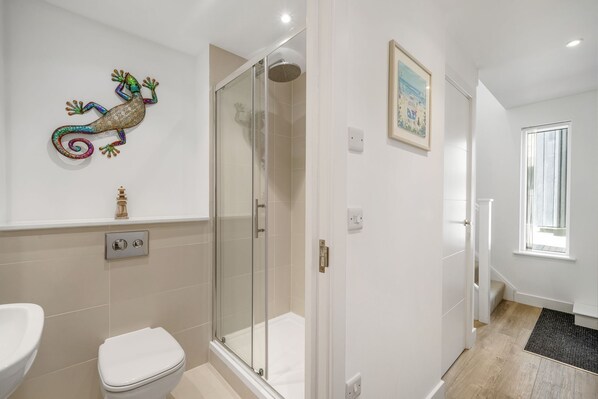 A bathroom with a glass-enclosed shower, a toilet, and a sink.