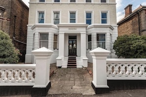 A two-story building with a symmetrical facade, a central entrance with steps, and a sign above the door. - Rock Pool Reach - modern, central, parking space (Broadstairs)
