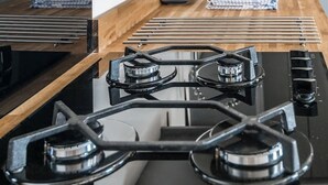 Een moderne keuken met een gasfornuis, een houten aanrechtblad en roestvrijstalen apparatuur.