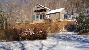 A two-story house with a large windowed front section and a smaller section on the side.