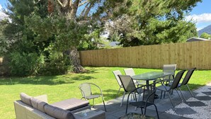 A patio area with a wicker sofa, a glass-top table, and metal chairs. - Very modern, new, clean, 3 Bedroom home 2 bathroom (Tūrangi)