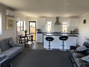 A modern kitchen with a central island, bar stools, and a dining area with a sofa and chairs.
