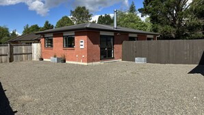 A small brick building with a metal roof, a wooden fence, and a gravel driveway. - Very modern, new, clean, 3 Bedroom home 2 bathroom (Tūrangi)