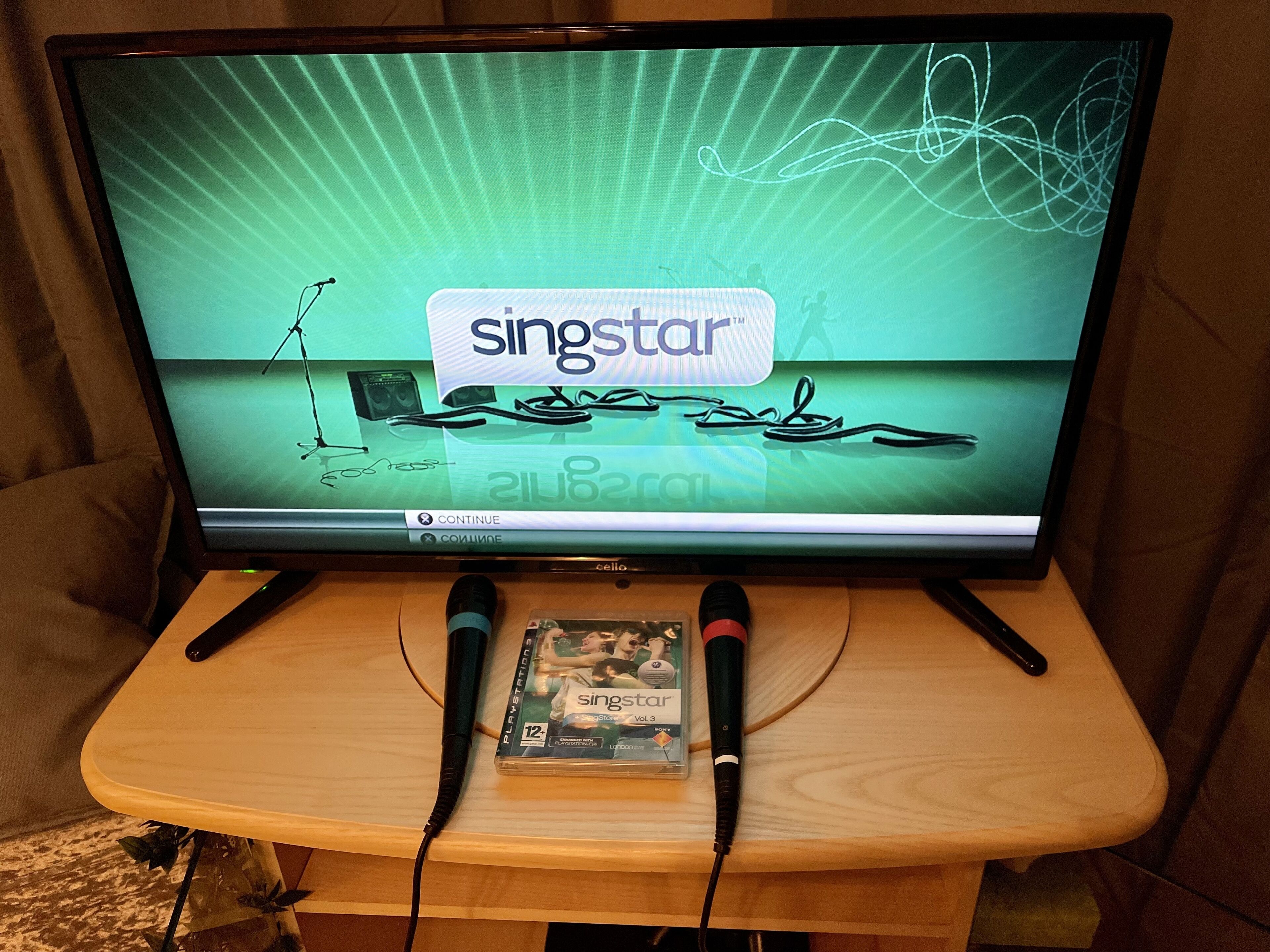 A television on a wooden stand displaying the 'SingStar' game interface.