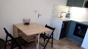 Ett kompakt kök med ett träbord och två stolar, en diskho och en diskmaskin.