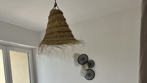Ett sovrum med en säng, en hängande lampa och dekorativ väggkonst.