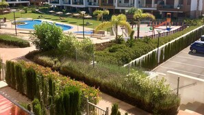 A residential building with multiple balconies, a swimming pool, and a playground.