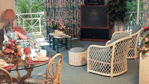 Un salón acogedor con muebles de mimbre, una mesa de vidrio y un televisor.