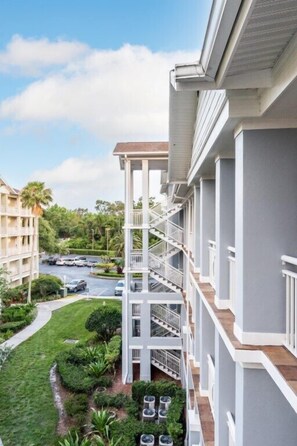 A multi-story hotel with balconies, a swimming pool, and lush landscaping.
