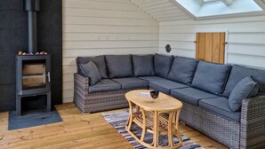 Ein gemütliches Zimmer mit einer Eckcouch, einem kleinen Tisch und einem Kaminofen.