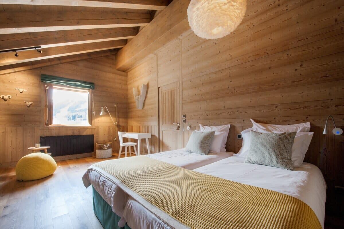 A cozy wooden room with a bed, a desk, and a window.