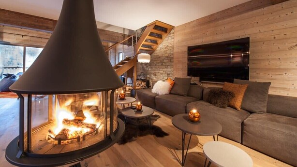 Ein gemütliches Wohnzimmer mit Kamin, einer Couch, einem Fernseher und einer Treppe.
