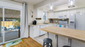 Una cocina moderna con armarios blancos, una isla de madera y electrodomésticos de acero inoxidable.