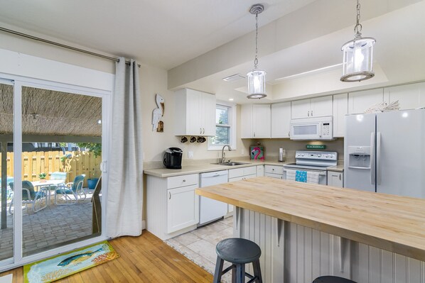 A modern kitchen with white cabinets, a wooden island, and stainless steel appliances.