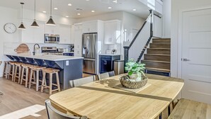 A modern kitchen with white cabinets, stainless steel appliances, and a wooden island with stools. - Brand New | Pool | lazy river | Competition mini golf | RH (Washington)