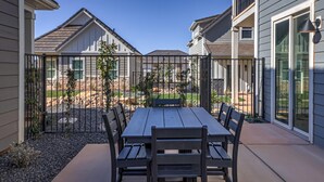 A patio with a table and chairs, surrounded by a fence, with houses in the background. - Brand New | Pool | lazy river | Competition mini golf | RH (Washington)