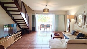 A living room with a TV, sofa, and staircase.
