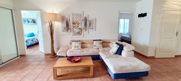 A living room with a sofa, a coffee table, and a floor lamp. There are abstract paintings on the wall.