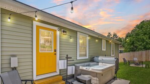 A house with a yellow front door, a hot tub, and string lights. - New home w/hot tub, fireplace, firepit - Less than 1/2 mi to Main St. (Waynesville)