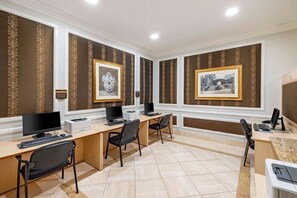 Uma sala de conferências com duas mesas, cadeiras, computadores e quadros nas paredes.