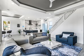 A modern living room with a sofa, coffee table, and a staircase. - Chic & Cozy River District Townhouse (Fort Myers)