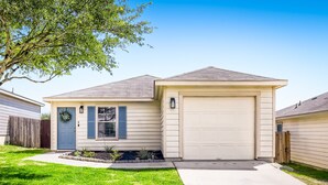 Une maison de plain-pied avec un garage, une pelouse devant et un petit jardin.