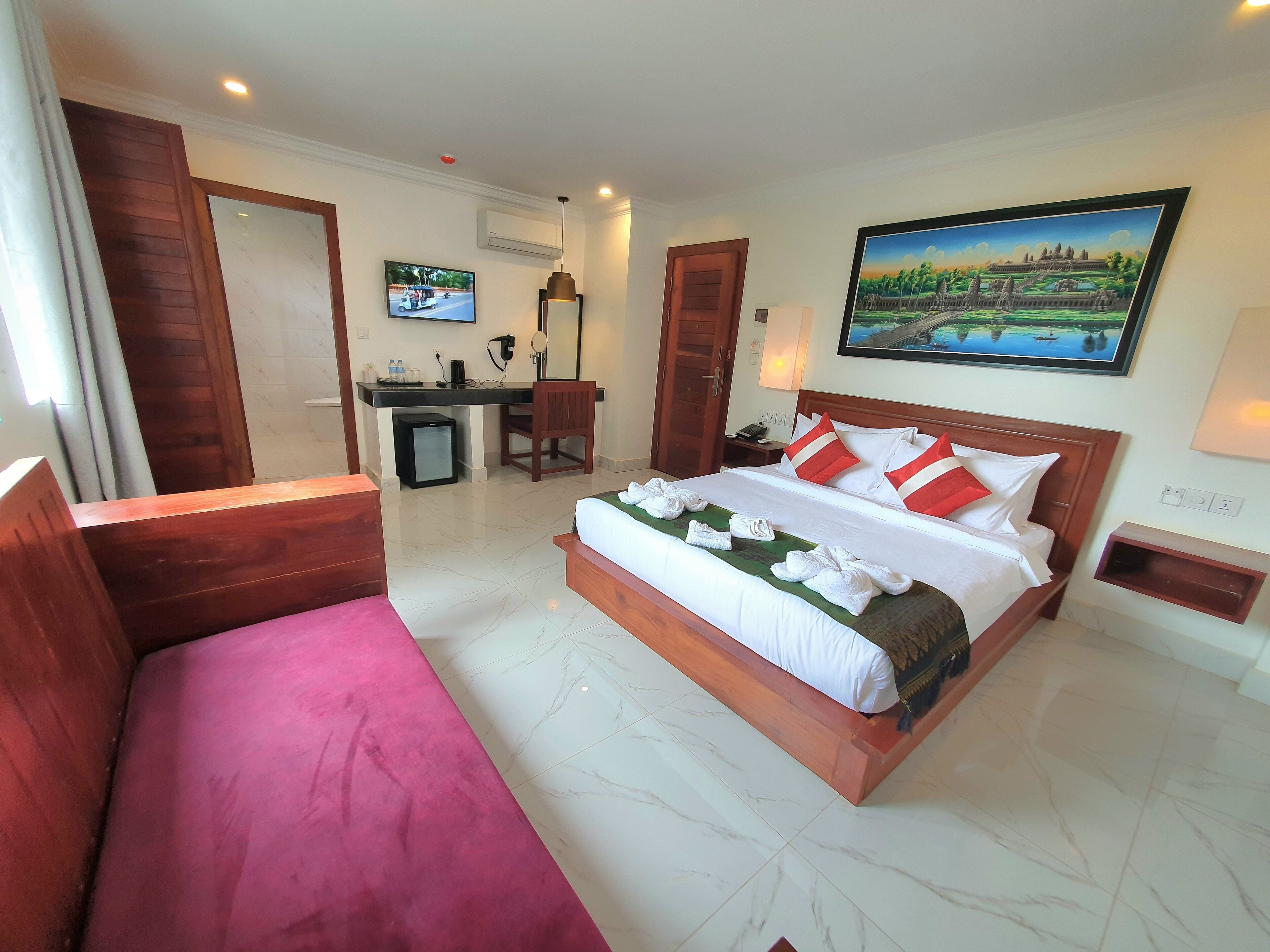 Una habitación de hotel con una cama grande, un escritorio, una silla y un refrigerador pequeño.