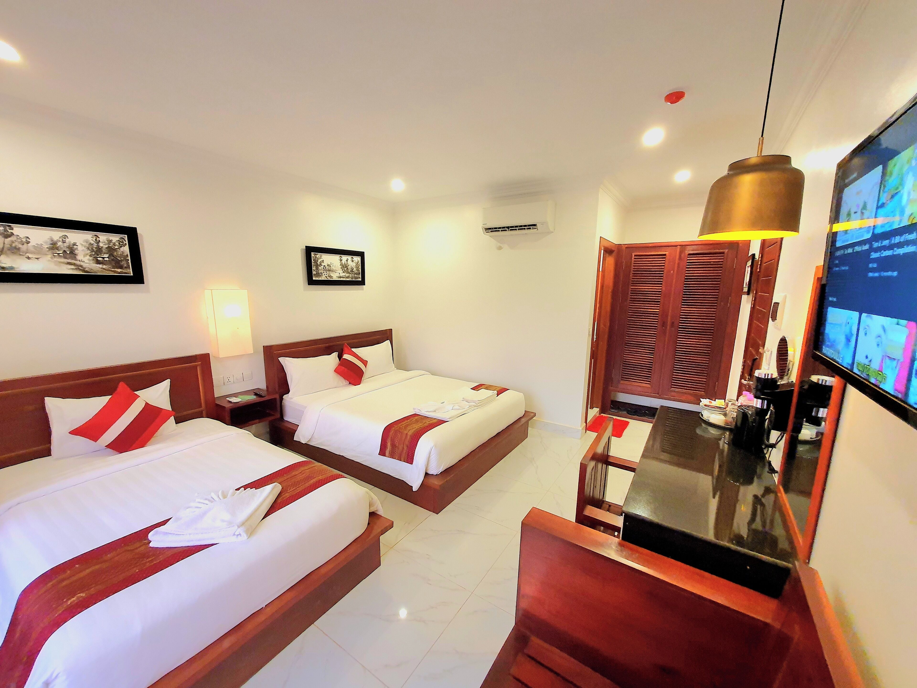 A hotel room with two beds, a desk, a TV, and a door leading to a balcony.