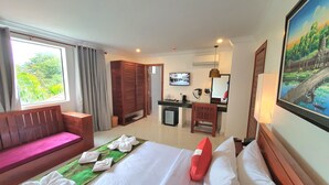 Ein Hotelzimmer mit Bett, Schreibtisch, Stuhl, Fernseher und einem fenster mit Vorhängen.