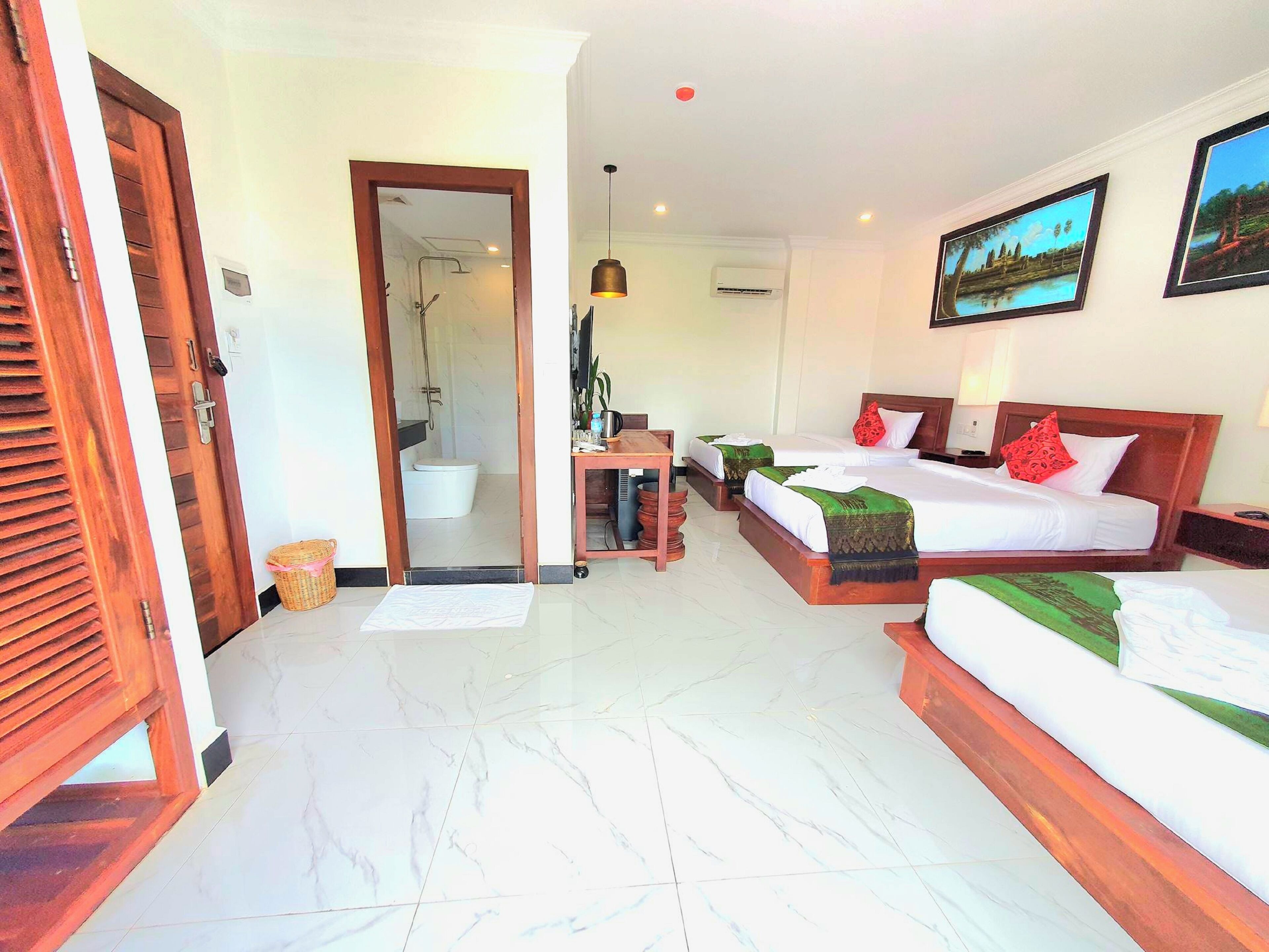A hotel room with two beds, a bathroom, a desk, and a mirror.