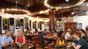 Ein Restaurant mit Holztischen und -stühlen, Deckenleuchten und Speisekarten an den Wänden.
