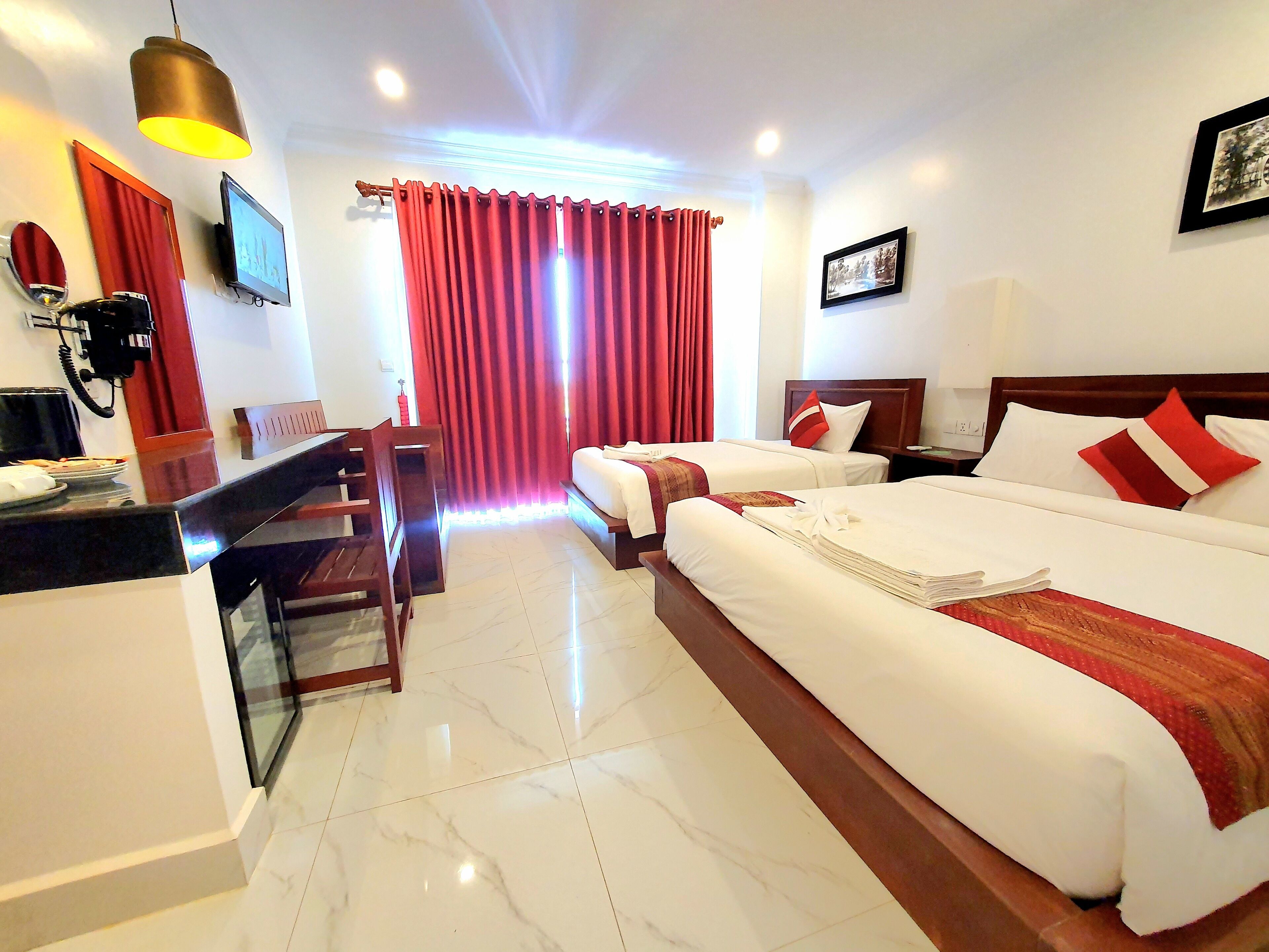 A hotel room with two beds, a desk, a chair, a telephone, and a television.